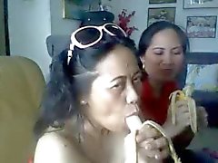Tailandêsa mulher madura que mostra a seus peitos grandes e chupando a banana